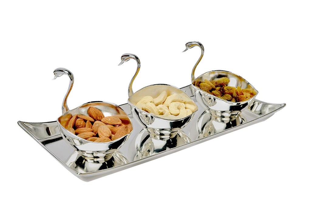 a set of three duck shaped bowls holding premium dry fruits placed on a wavy border silver tray
