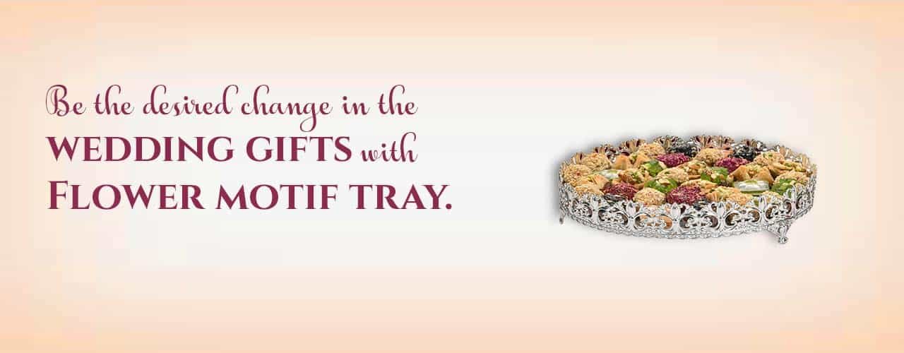 A sentence with a picture of silver plated tray & sweets saying- be the desired change in the wedding gifts with flower motif tray