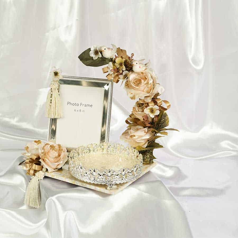 an exclusive gift hamper adorned with flowers & ribbons consisting of silver photo frame & a designer silver tray