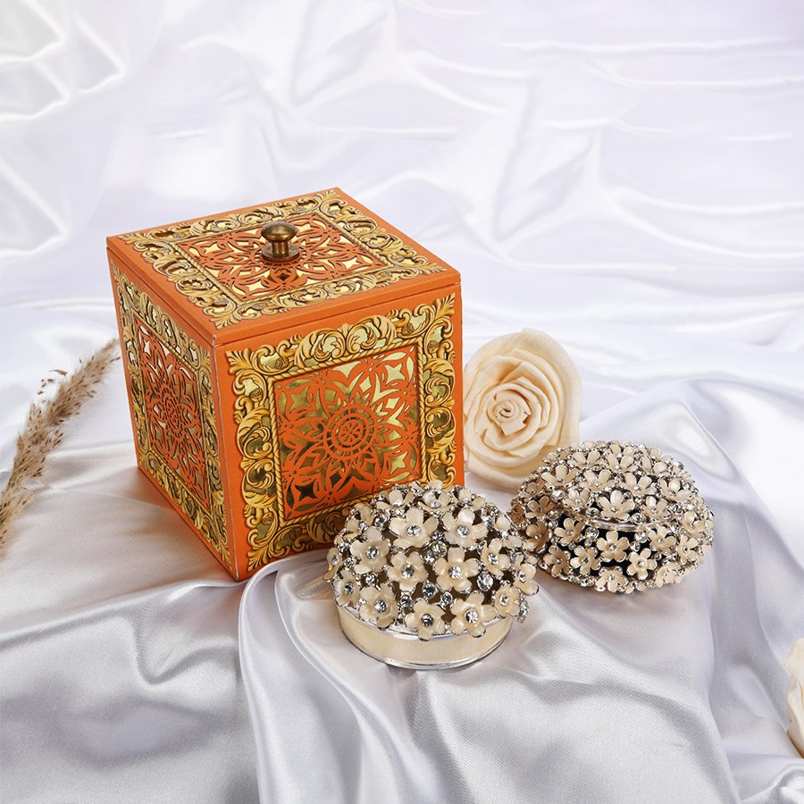 Enameled flowers trinket box set with a majestic gift box and a peach colored rose appear in the background.