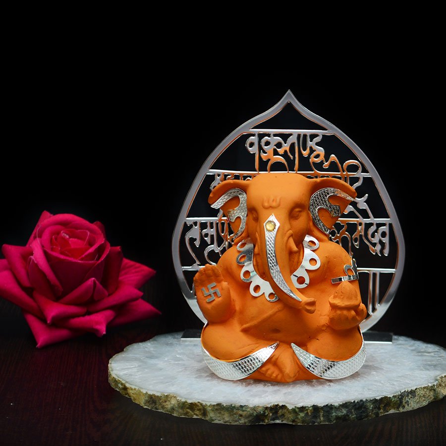Lord Ganesh's sitting figurine in saffron color with matra cutout on silver plated leaf cutout in silver plating